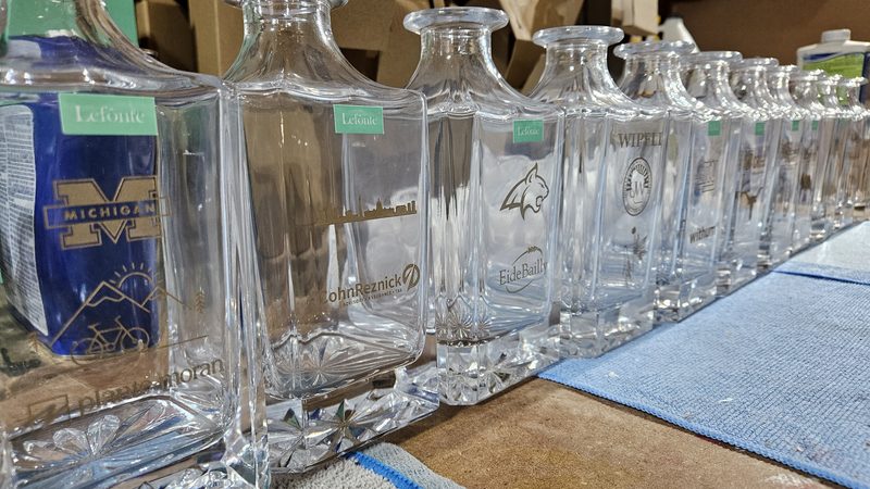 Row of etched glass bottles lined up after a production run