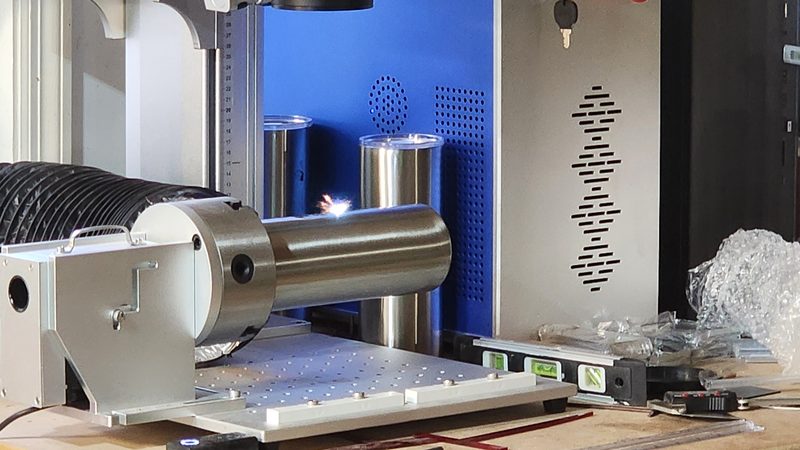 Stainless tumbler mounted on the fiber laser rotary attachment mid-engrave